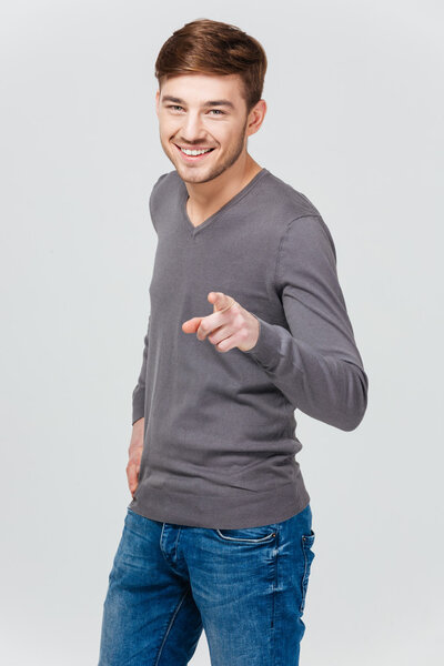 Cheerful attractive young man smiling and pointing on you