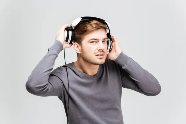Przystojny młody mężczyzna w szary sweter startu słuchawki — Zdjęcie stockowe