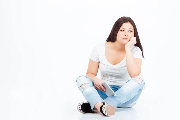 Pensive casual woman sitting on the floor with tablet computer — Stock Photo, Image