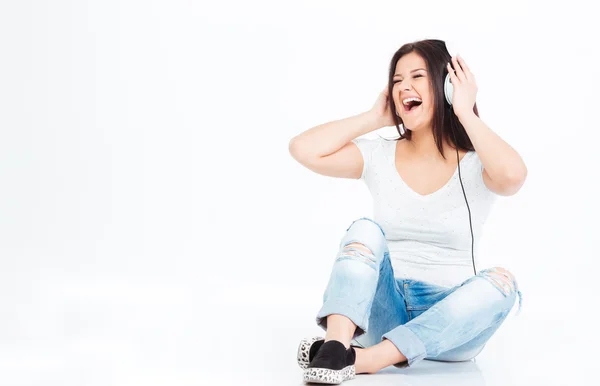 Женщина сидит на полу и слушает музыку в наушниках — стоковое фото
