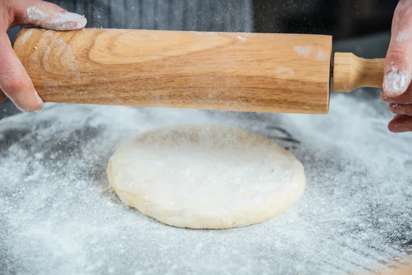 Male hands rolling out dough on the table — Stock Photo, Image