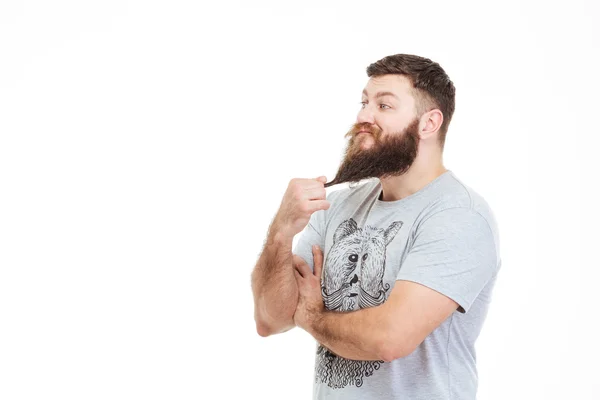 Bonito homem atencioso de pé e tocando sua barba — Fotografia de Stock