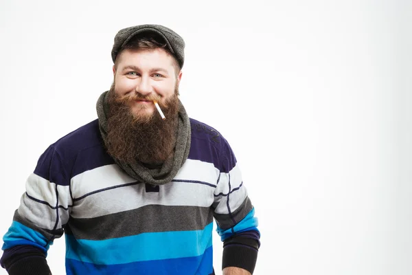 Улыбающийся бородатый мужчина в кепке и шарф с сигаретой — стоковое фото