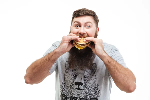 Fome barbudo jovem comendo hambúrguer — Fotografia de Stock