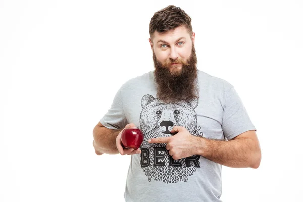 Sorrindo barbudo homem segurando uma maçã e apontando sobre ele — Fotografia de Stock