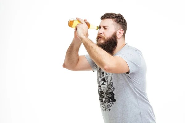 Игривый бородатый мужчина держит бутылку пива, как телескоп — стоковое фото
