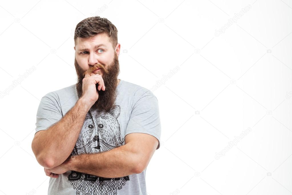 Pensive handsome bearded man standing with hands folded and thinking