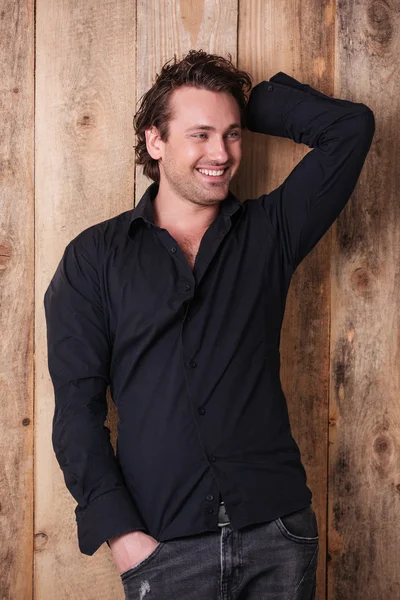 Uśmiechający się atrakcyjny młody mężczyzna w czarnej koszuli stojący i pozowanie — Zdjęcie stockowe
