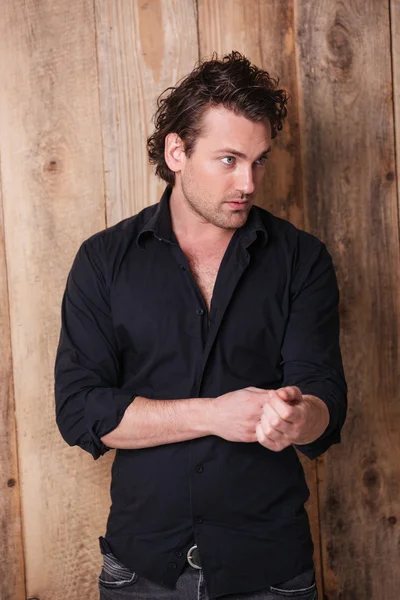 Serious confident man in black shirt standing and looking away — Stock Photo, Image