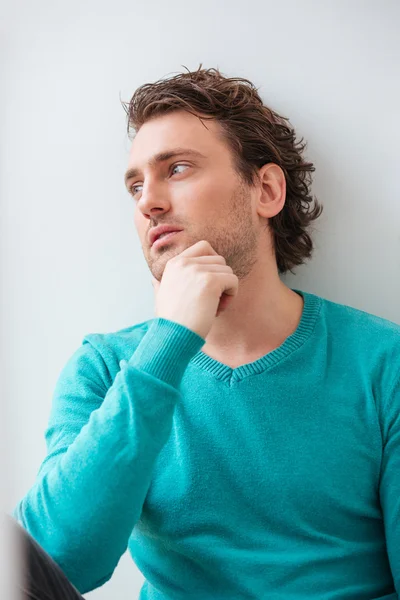 Nachdenklicher junger Mann mit lockigem Haar, der aus dem Fenster blickt — Stockfoto