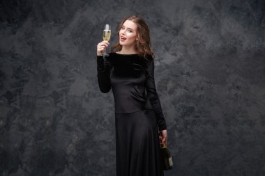 Şişe ve kadeh şampanya tutan neşeli güzel genç kadın 