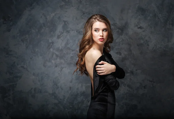 Beautiful tender young woman in black dress with open back — Stock Photo, Image