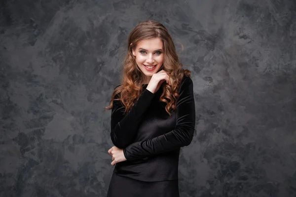 Cheerful cute young woman with curly hair in black dress — Stock Photo, Image