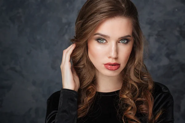 Beautiful young woman touching her curly long hair — Stock Photo, Image