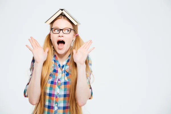 Verbaasd vrouwelijke student met boek op hoofd — Stockfoto