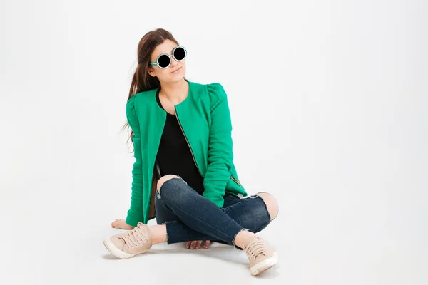 Mujer sonriente con chaqueta verde, jeans rasgados y gafas de sol —  Fotos de Stock