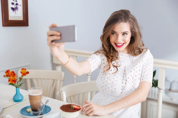 Mosolygó gyönyörű nő vesz selfie smartphone ül a café — Stock Fotó