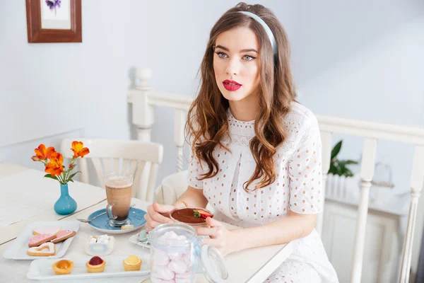 Thoghtful jovem mulher comendo sobremesa e pensando em café — Fotografia de Stock