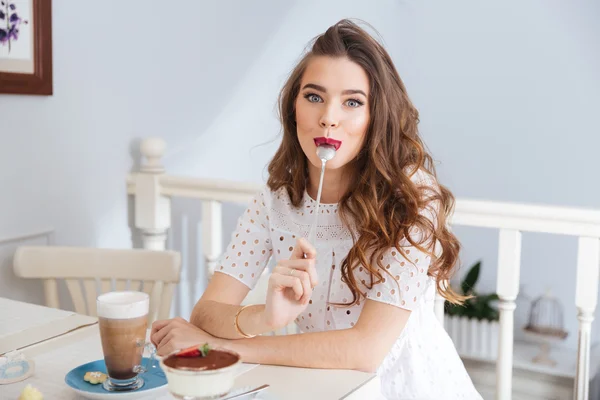 Zábavný žena sedí v kavárně s lžičkou v ústech — Stock fotografie