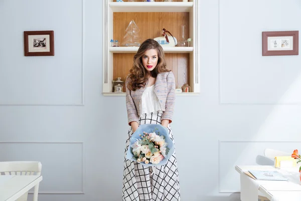 Schöne Frau steht und hält Blumenstrauß im Café — Stockfoto