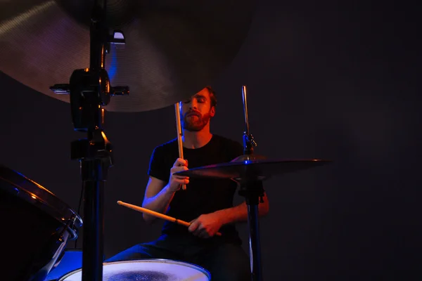 Atractivo baterista barbudo con los ojos cerrados disfrutando tocando la batería — Foto de Stock