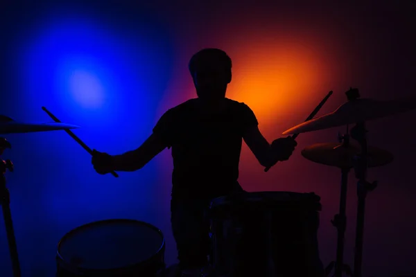 Silhueta de homem baterista sentado e tocando bateria com paus — Fotografia de Stock