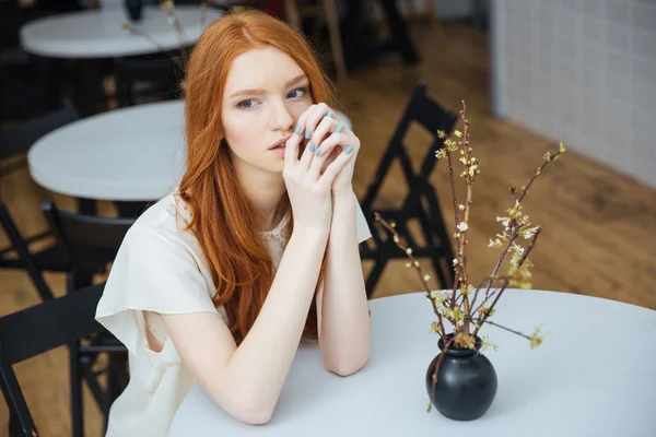 Fundersam attraktiv ung kvinna sitter vid bordet i café — Stockfoto