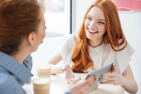 Två glada charmig ung kvinna med tabletten i café — Stockfoto
