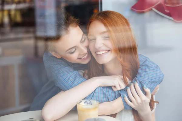 Dos lindas mujeres felices abrazándose en la cafetería —  Fotos de Stock