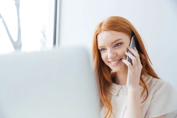 Mujer feliz uso de la computadora portátil y hablar por teléfono celular en la cafetería —  Fotos de Stock