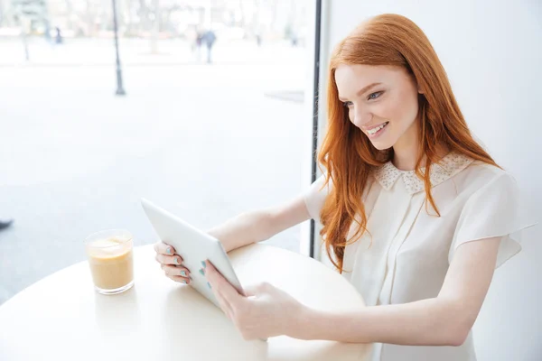 Leende kvinna sitter och använda Tablet PC i café — Stockfoto