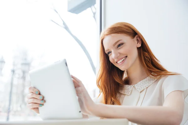 Uśmiechający się uroczy rudy młoda kobieta z tabletem w kawiarni — Zdjęcie stockowe