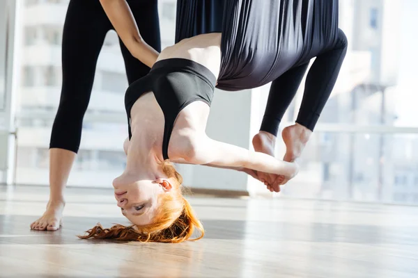 Pretty woman doing pose of antigravity yoga with personal trainer — Stock Photo, Image