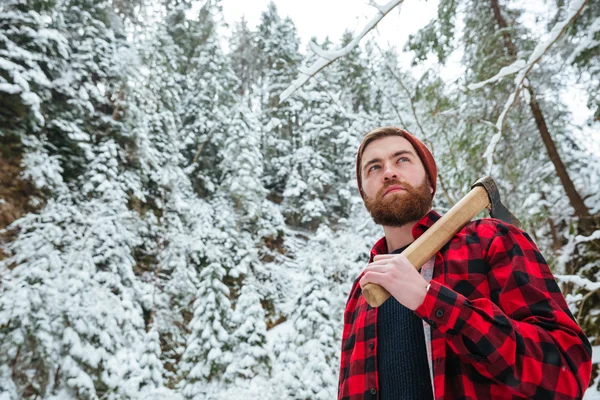 Hombre serio sosteniendo hacha y caminando en el bosque de invierno — Foto de Stock