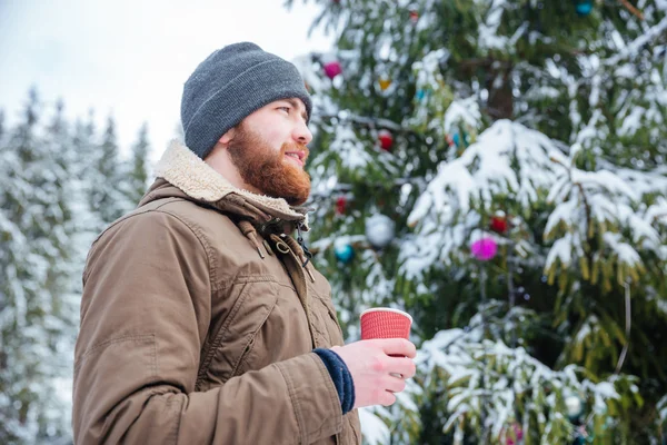 Homem de pé perto da árvore de natal decorada e beber café ao ar livre — Fotografia de Stock