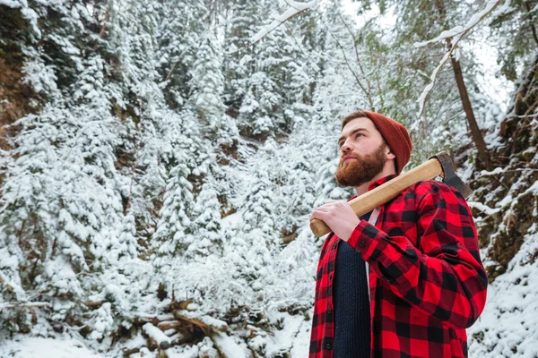 Schöner bärtiger junger Mann mit Axt im Winterwald — Stockfoto