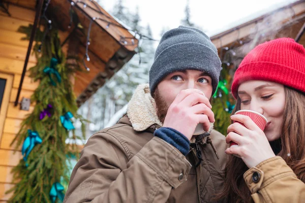 Мужчина и женщина пьют горячий кофе на рождественском рынке — стоковое фото