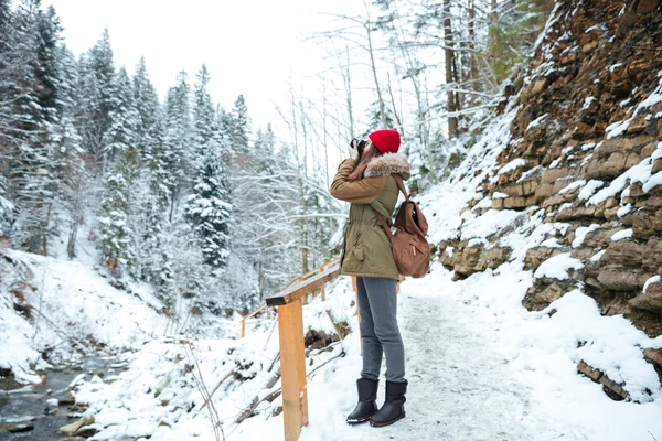 Mujer bonita fotógrafa tomando fotos en el bosque de invierno en las montañas — Foto de Stock