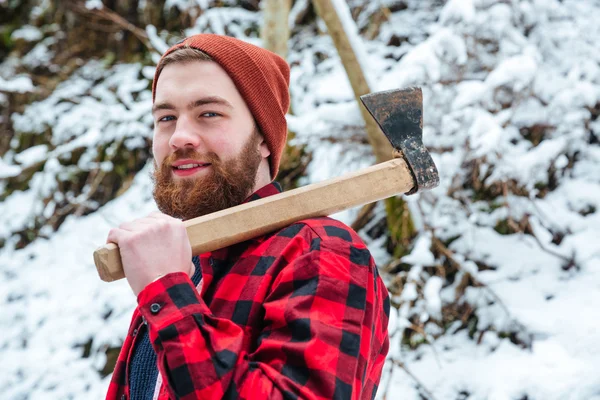 Lächelnder attraktiver bärtiger Mann mit Axt im Winterwald — Stockfoto