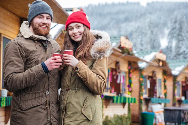 Pareja feliz bebiendo café en el mercado de Navidad en el resort de montaña — Foto de Stock