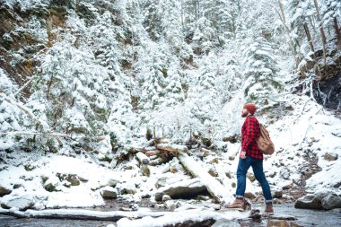 Adam kış orman Nehri yakınında yürüyüş sırt çantası ile