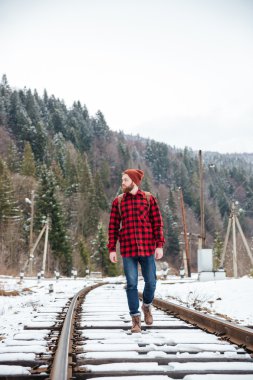 Demiryolu üzerinde yürüyen hipster adam