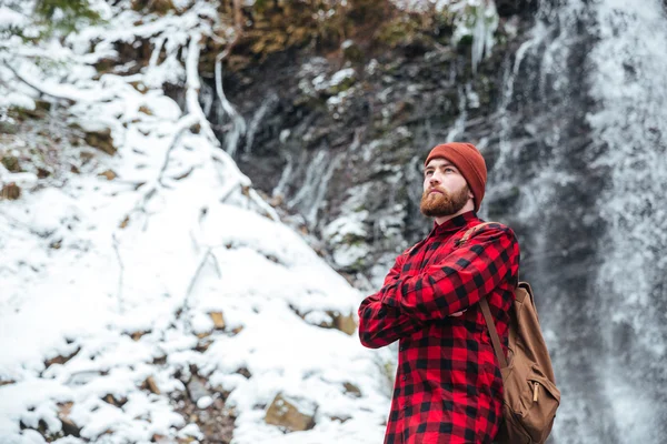 Hombre con mochila de pie cerca de una cascada — Foto de Stock