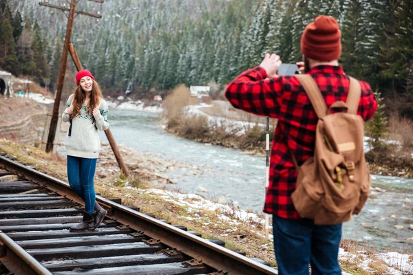 Young man taking photos of girlfriend on railway track — Stock Photo, Image