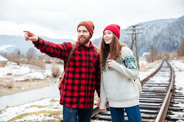 Щасливий бородатий чоловік стоїть і показує напрямок до своєї дівчини — стокове фото