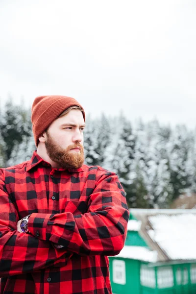 Ernster bärtiger junger Mann, der mit gefalteten Händen im Winter steht — Stockfoto