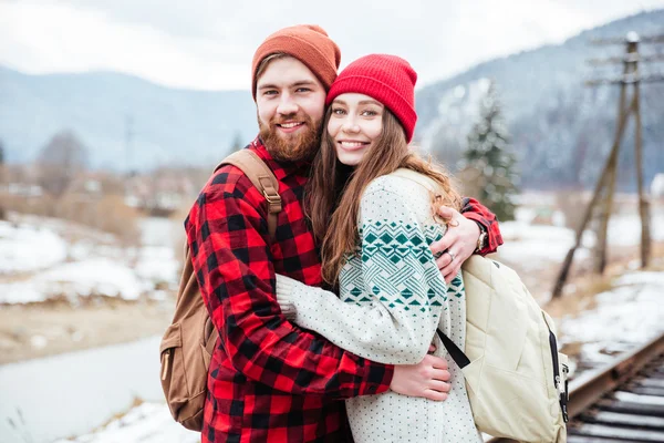 Jovem casal feliz com mochilas abraçando nas montanhas — Fotografia de Stock