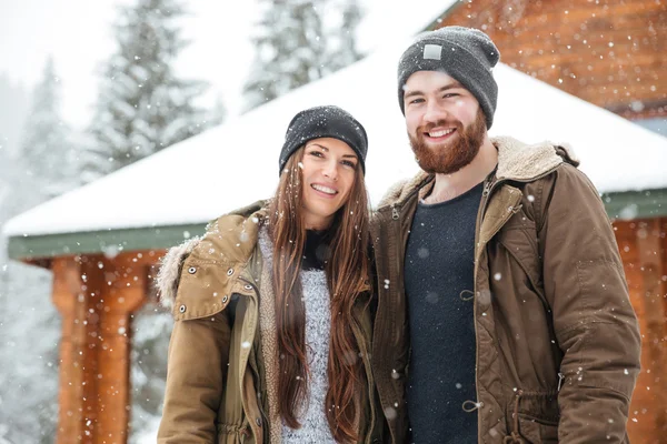 Couple debout devant la cabane en rondins hiver — Photo