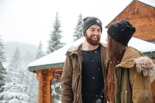 Пара стоїть біля дерев'яного котеджу і сміється — стокове фото