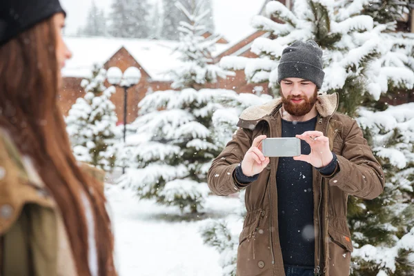 Άνθρωπος λήψη φωτογραφιών από τη φίλη με smartphone το χειμώνα — Φωτογραφία Αρχείου